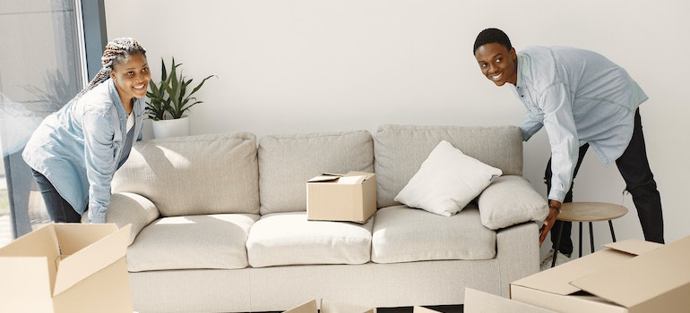 A couple holding a sofa in effort to estimate the storage unit size they need