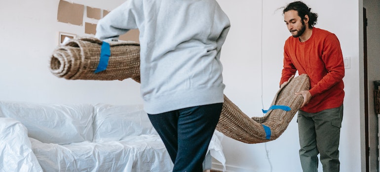 Couple taking a rolled carpet out and embracing minimalism with self storage