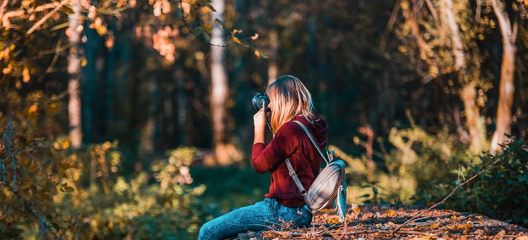 a girl using a camera in a forest