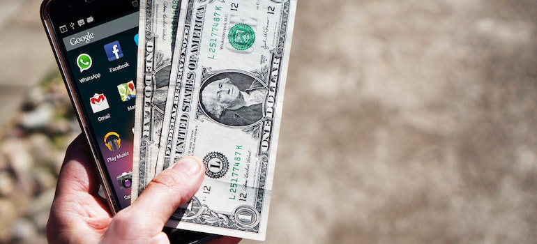 person holding money and a phone