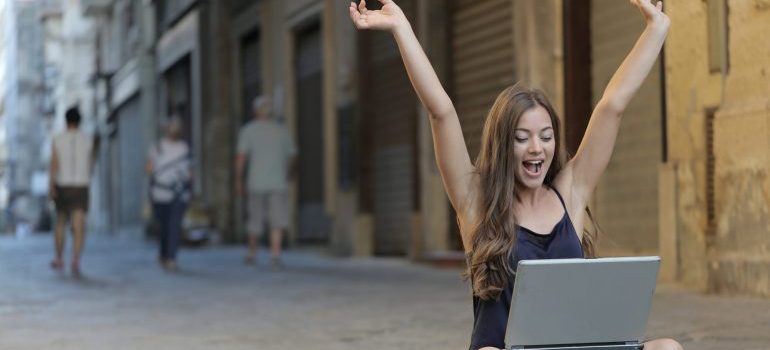 Happy girl with her laptop on the street
