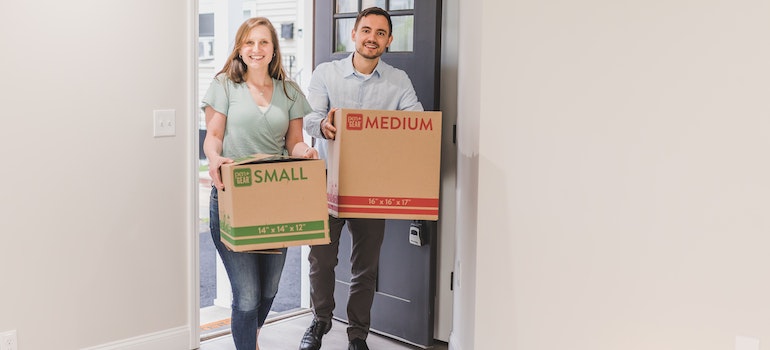 A Couple Carrying Boxes in Their New Home