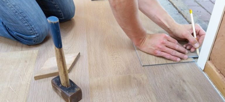 A person using a pencil to mark floor tiles