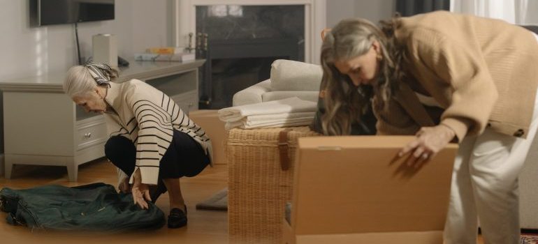 Two elderly women packing and talking about Newcastle's seniors' transition to smaller living spaces