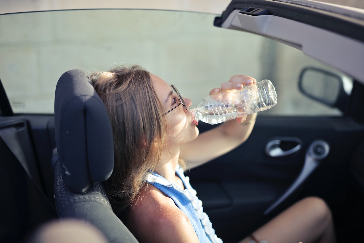a girl drinking water in her car