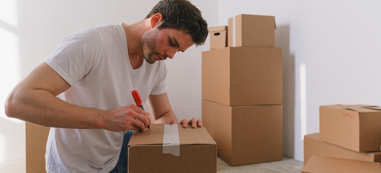 A Man Writing a Label on a Box