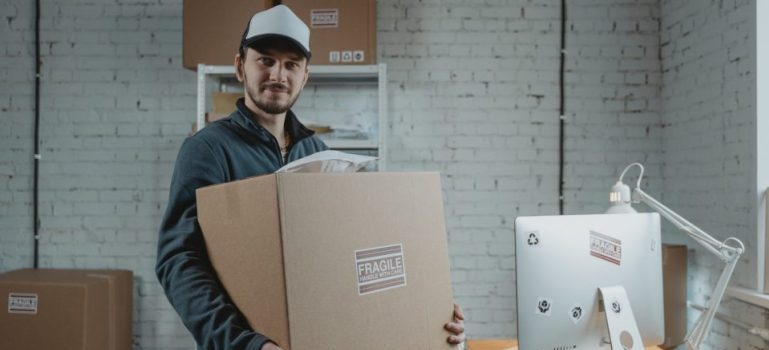 Man holding a box considering between portable storage vs internal business storage