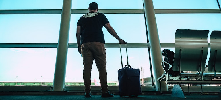 Man holding small luggage at an airport thanks to mobile storage for Lynnwood jet setters