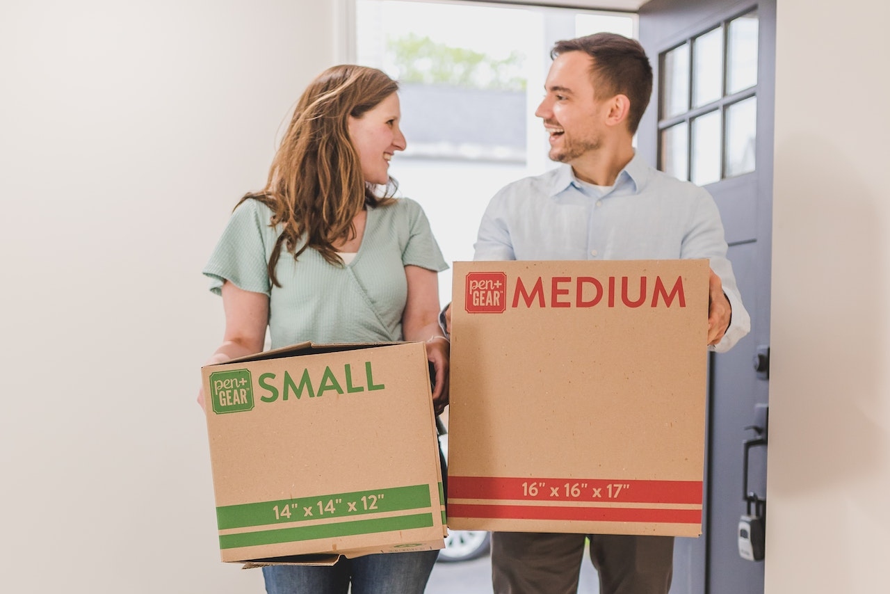 Man and Woman merging two households are Holding Brown Cardboard Boxes