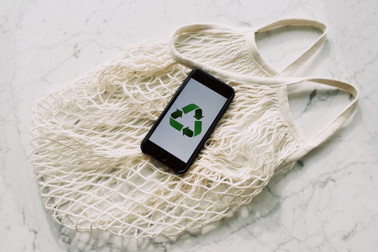 Mobile phone with green recycling sign and mesh bag