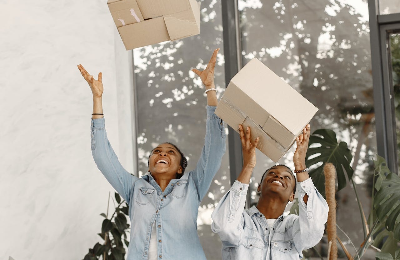 A couple tossing cardboard boxes in the air