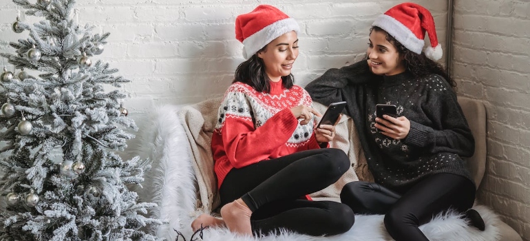 Two women in Christmas hats sitting and drinking coffee