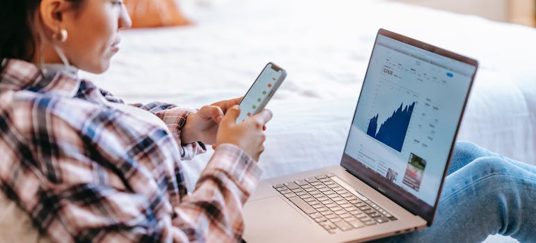 A woman with smartphone and laptop explores Seattle's housing market