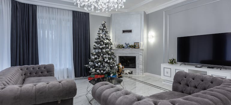 Spacious living room with comfy couch and armchair decorated with Christmas tree