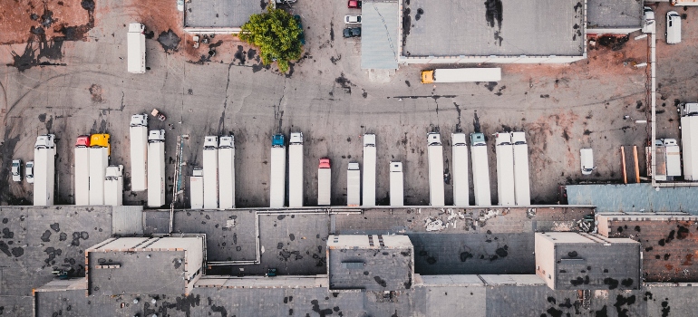 Aerial view of trucks on gray commercial building under impact of climate on storage