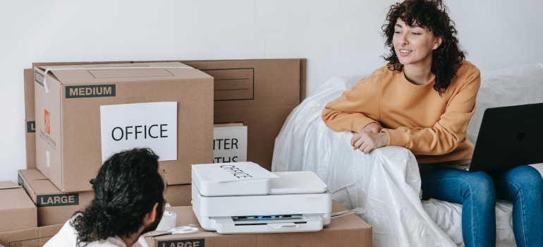 A couple sitting next to packed boxes