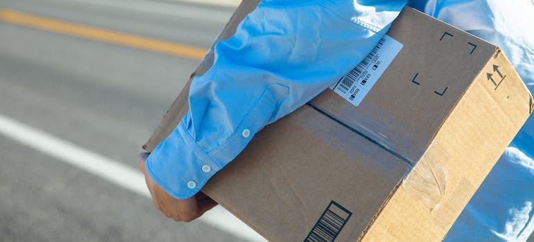 A person carrying a brown box on a road from Seattle storage for sustainable holidays