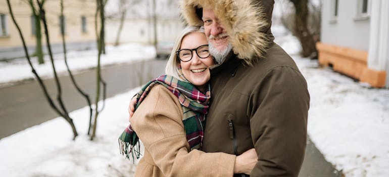 A happy elderly couple in winter clothes holding each other