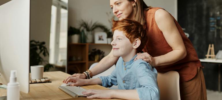 A boy and his mother in front of clean desk and a monitor
