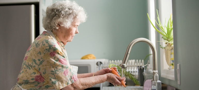 An elderly woman washing vegetables in assisted living in Everett