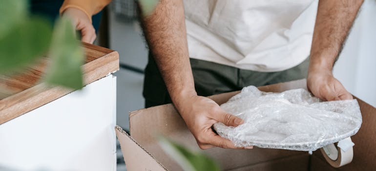 A man putting a wrapped plate in the box
