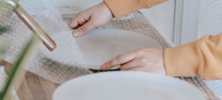 A woman wrapping plates in bubble wrap