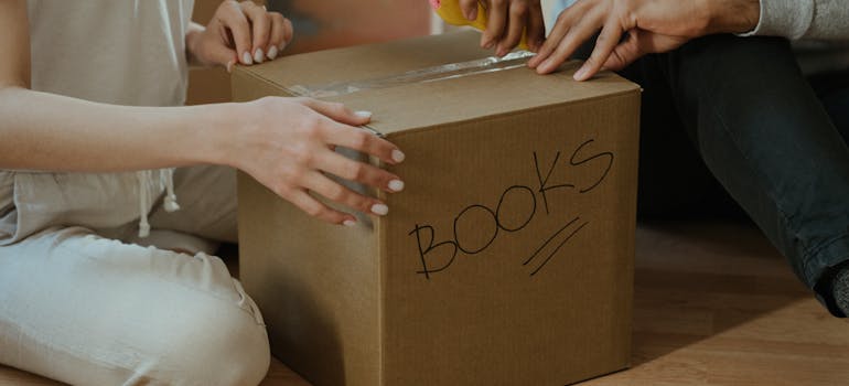 A couple taping a box labeled Books