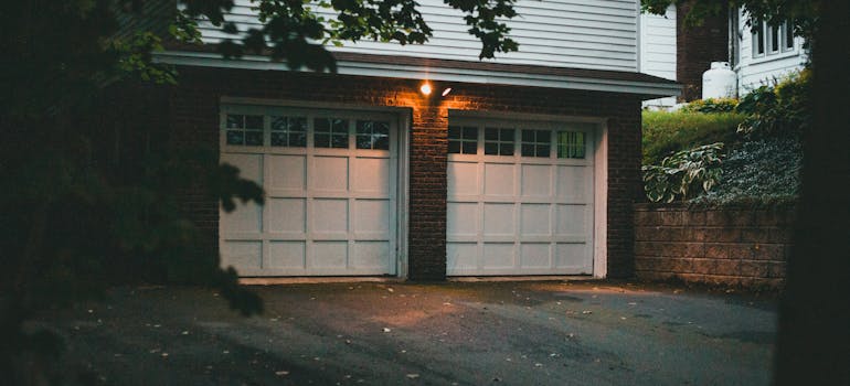 A pair of white garage doors in a brick house