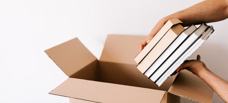 A man shows how to prepare books for long term storage by placing them in a box