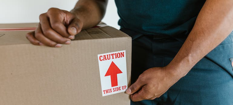 A man holding a box labeled Caution-this side up.