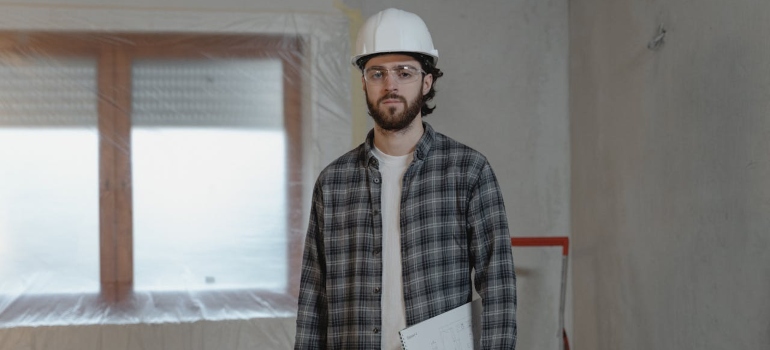 A builder in white hat standing in a remodeled room