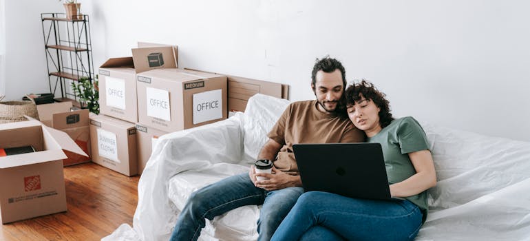 Couple Sitting On A Couch Browsing On Computer