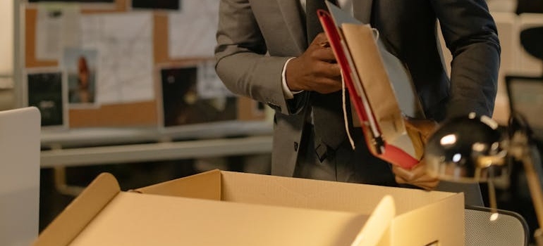 Man in Gray Suit putting Files and Documents in a box