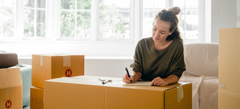 Woman labeling a box near large window