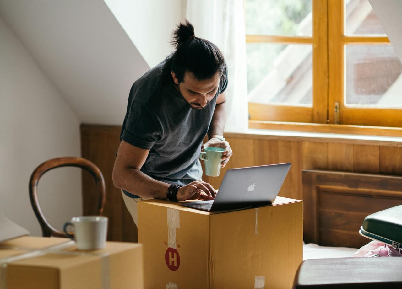 One of the young WA pros relocating for a job is using a laptop while packing