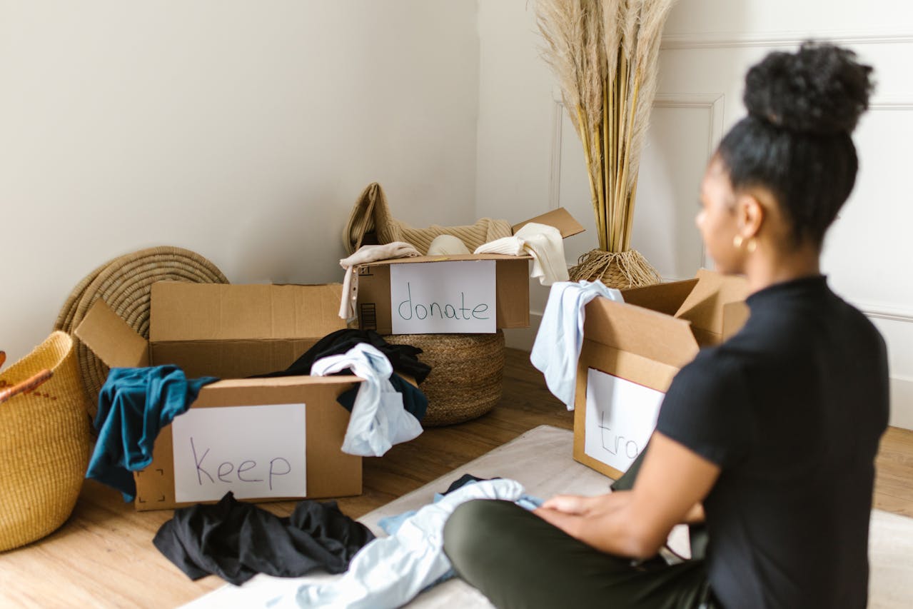 A Woman Sitting in front of Cardboard Boxes thinks how to reduce waste while organizing home