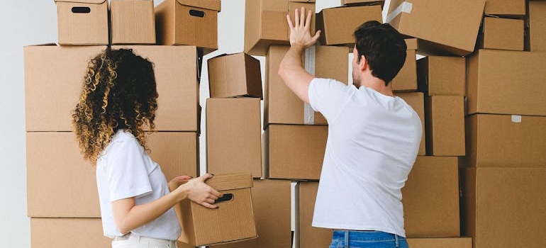 A couple is stacking cardboard boxes