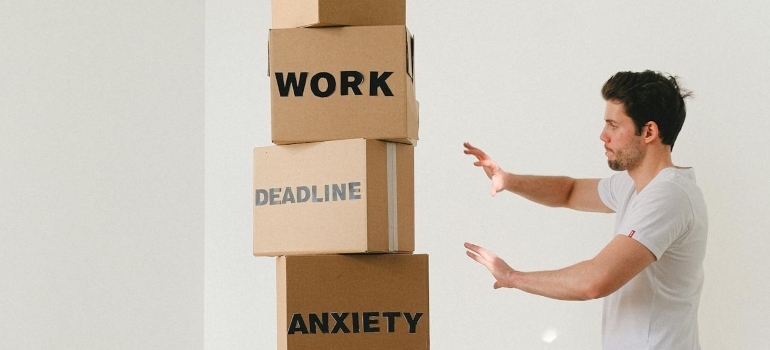 Man near carton boxes with many different words about stress