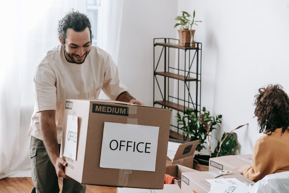 Man in White Crew Neck T-shirt Carrying A Brown Box