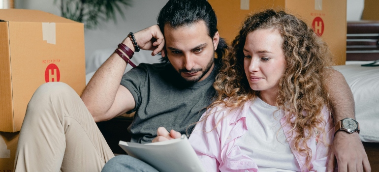 Thoughtful couple writing in notebook about space saving packing tips