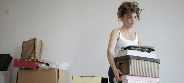 Concentrated woman carrying stack of cardboard boxes for relocation
