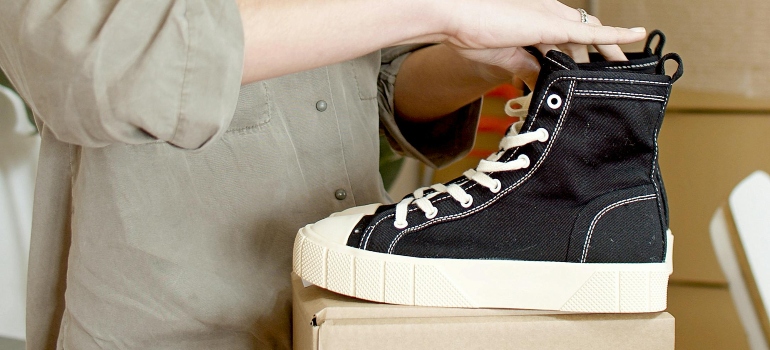Woman Fixing the Black Shoes on Top of the Box and showing how to store your shoes