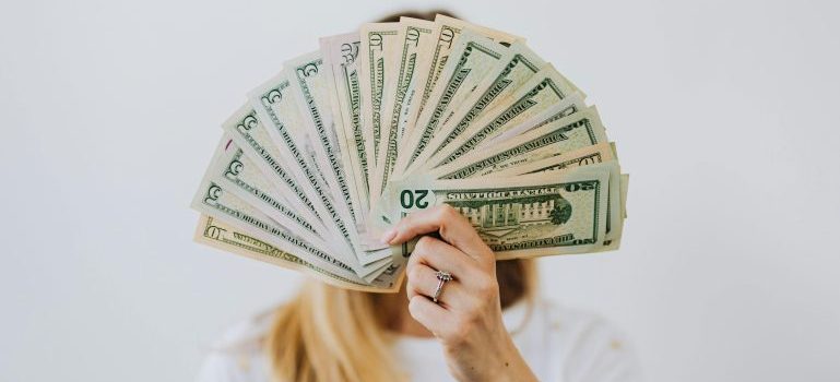 Woman holding up different dollar bills in front of her face