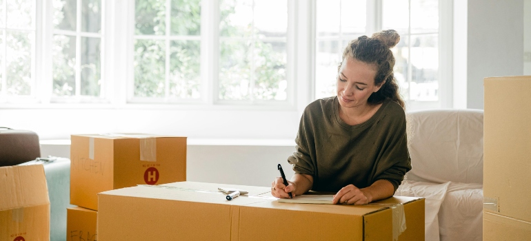 Woman signing box near large window in sunlight at home