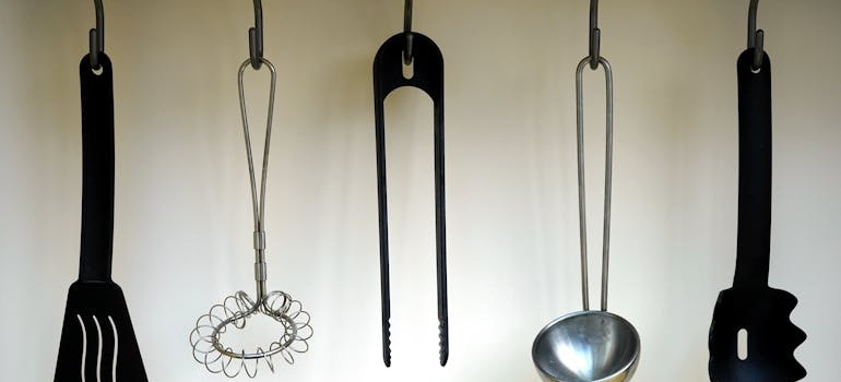 Black plastic spatulas hanged on black hooks after decluttering your kitchen