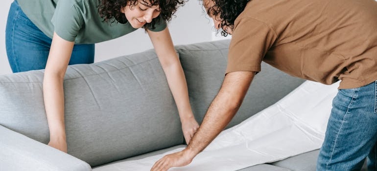 a couple covering a sofa with a white sheet
