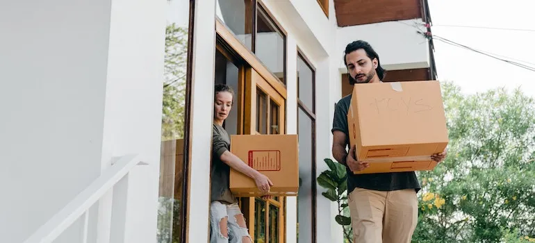 A couple carrying moving boxes