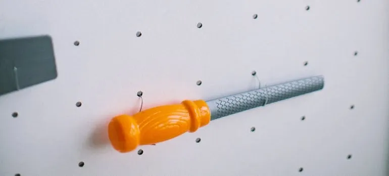 A metal file hanging on a white pegboard